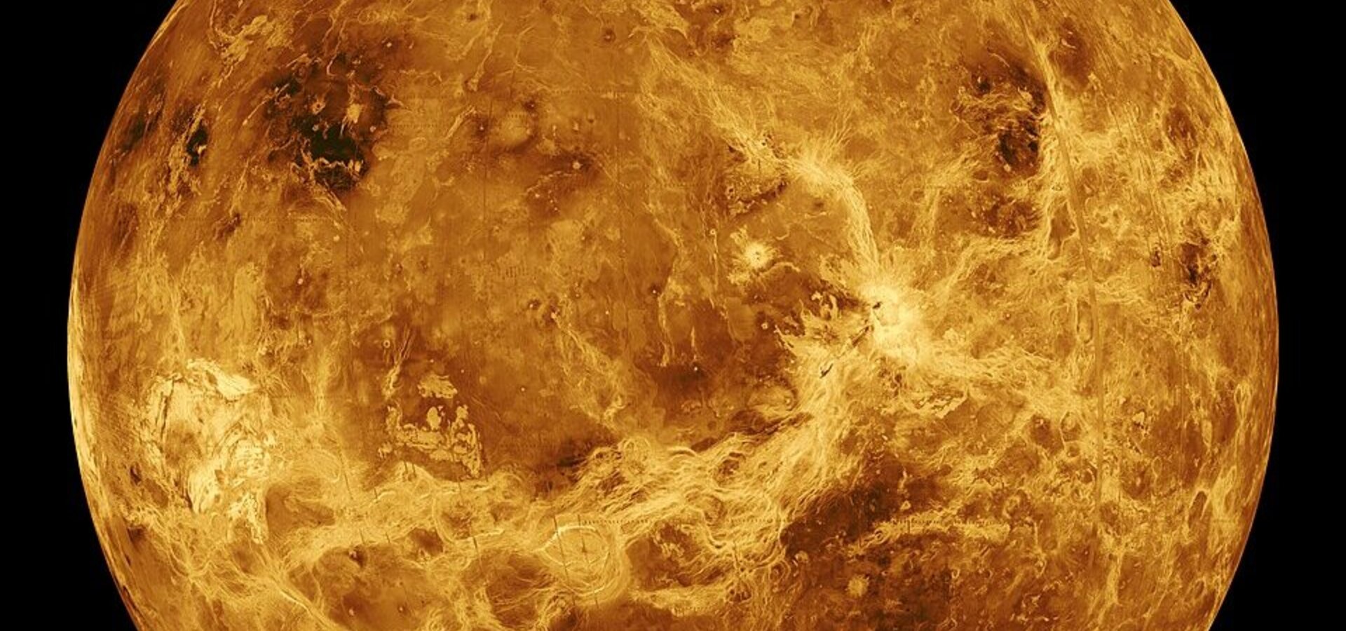 Die Darstellung zeigt den Planeten Venus, der von einer dichten, gelb-orangefarbenen Atmosphäre umgeben ist. Die Oberfläche ist von felsigen und vulkanischen Merkmalen geprägt, die durch Wolken aus Schwefelsäure verborgen sind. Die dunkelsten Stellen deuten auf unterschiedliche geologische Strukturen hin.