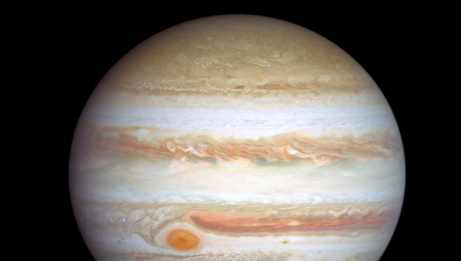 Das Bild zeigt den Planeten Jupiter mit seinen charakteristischen Streifen und dem großen roten Fleck. Neben Jupiter ist die Erde klein dargestellt. Der Hintergrund ist schwarz, was den Kontrast zwischen den Himmelskörpern verstärkt.