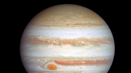 Das Bild zeigt den Planeten Jupiter mit seinen charakteristischen Streifen und dem großen roten Fleck. Neben Jupiter ist die Erde klein dargestellt. Der Hintergrund ist schwarz, was den Kontrast zwischen den Himmelskörpern verstärkt.