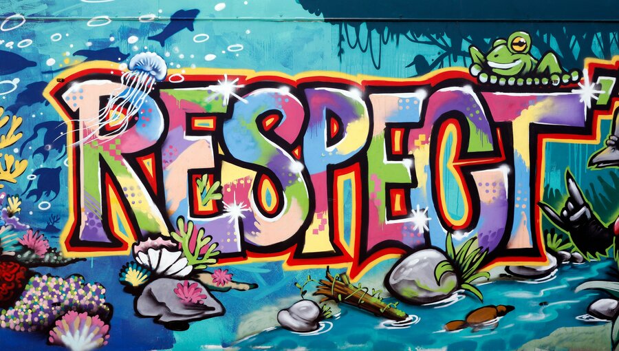 Das Bild zeigt ein farbenfrohes Wandgemälde mit dem Wort "RESPECT". Umgeben ist es von maritimem Leben, darunter Korallen und eine meduse. Die lebendigen Farben und verspielten Elemente unterstreichen die Botschaft des Respekts für die Meereswelt.