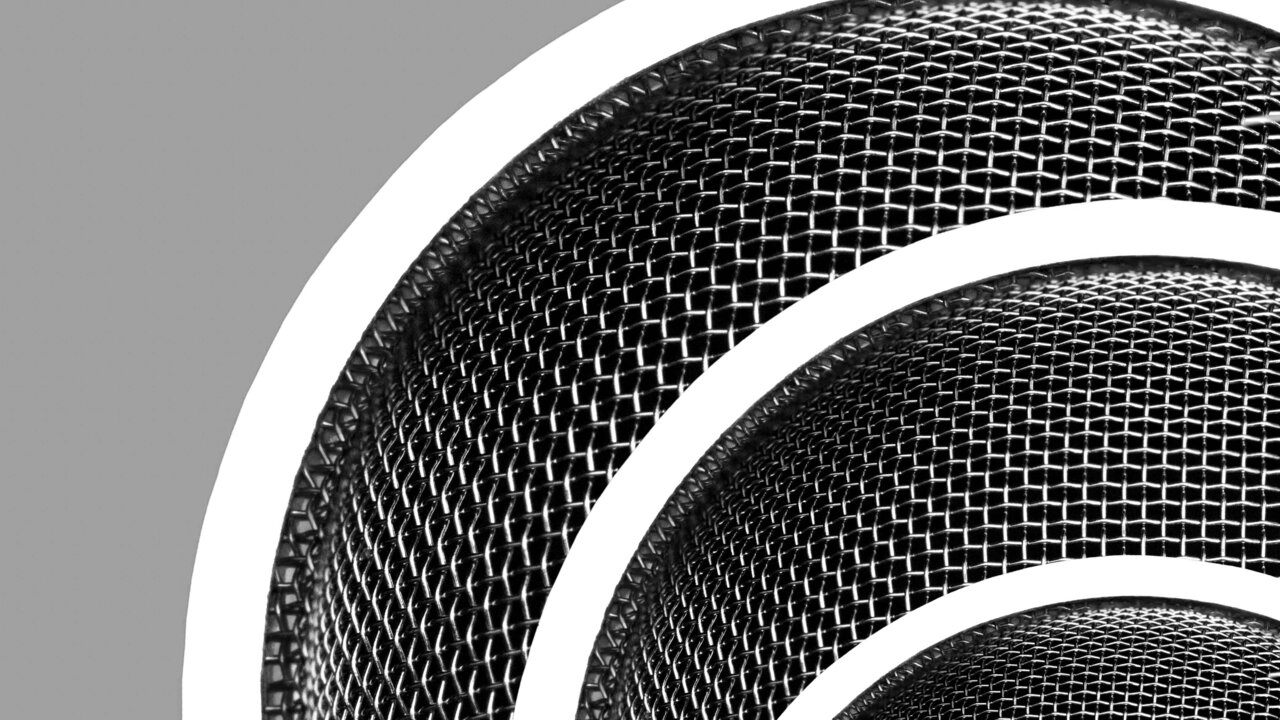 Ein stylisiertes Bild eines Mikrofonkorbs mit einem feinmaschigen Gitterdesign. Der Hintergrund ist grau, während der Mikrofonkorb in einer dynamischen Anordnung dargestellt wird. Die Formen verlaufen kreisförmig und betonen die Struktur des Gitters.