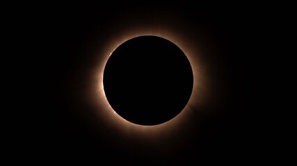 Ein perfekter Ring aus Licht umgibt eine dunkle, runde Scheibe, die die Sonne während einer totalen Sonnenfinsternis verdeckt. Der Hintergrund ist tiefschwarz, was den Kontrast zwischen dem Lichtkreis und der Sonne verstärkt.