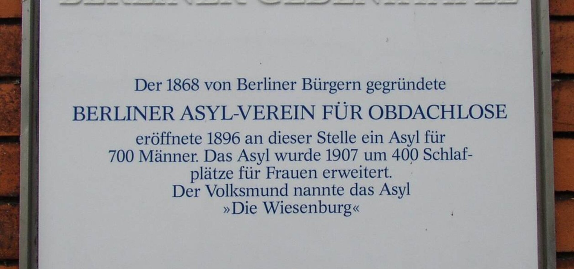 Berliner Gedenktafel, die an den 1868 gegründeten Berliner Asyl-Verein für Obdachlose erinnert. Die Tafel beschreibt die Eröffnung eines Asyls im Jahr 1896 für 700 Männer und die Erweiterung im Jahr 1907 um 400 Schlafplätze für Frauen. Der Name „Die Wiesenburg“ wird erwähnt.